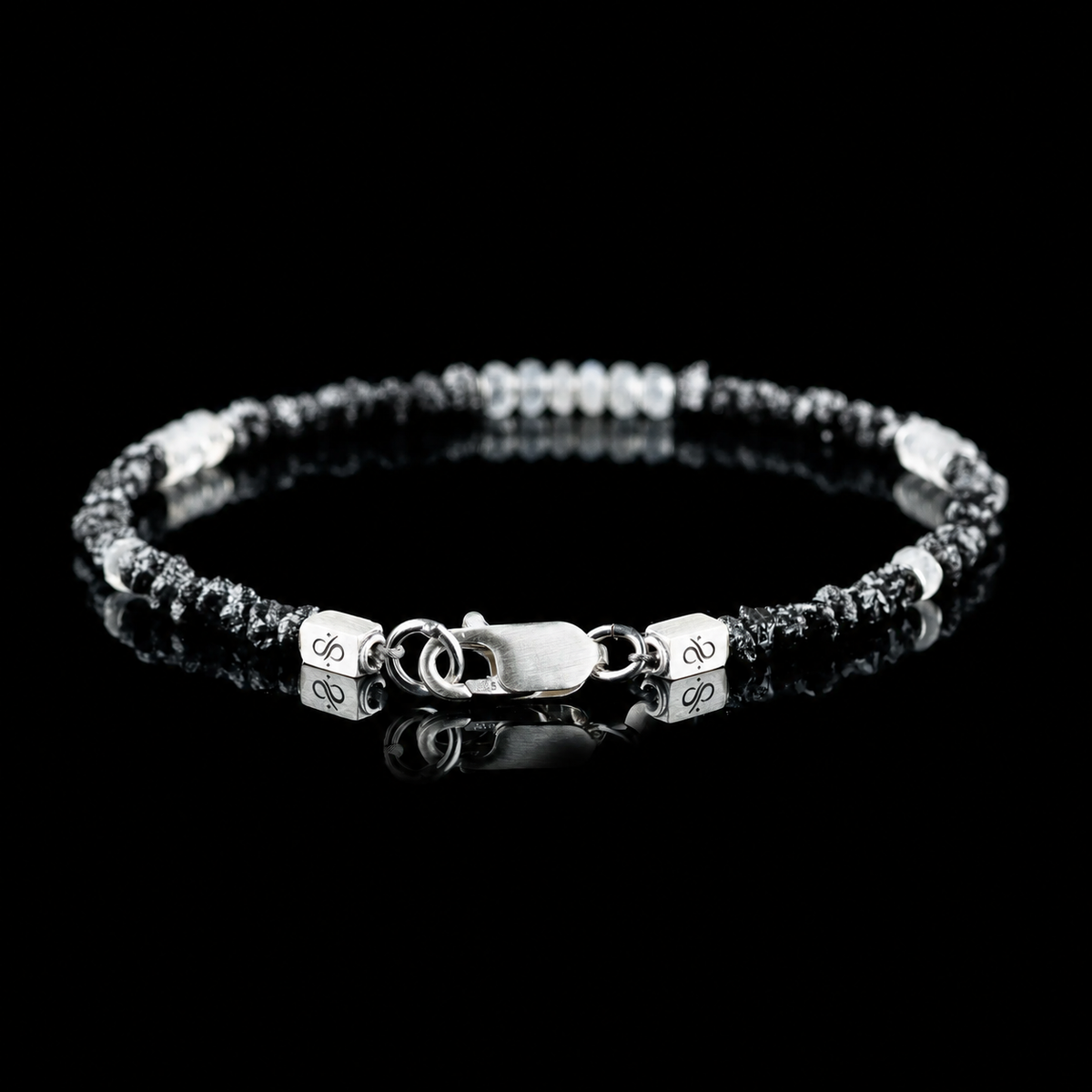 Back view of Raw Black Diamond - Moonstone Bracelet I (3-4mm), showing the clasp and branded end pieces on a black reflective surface.