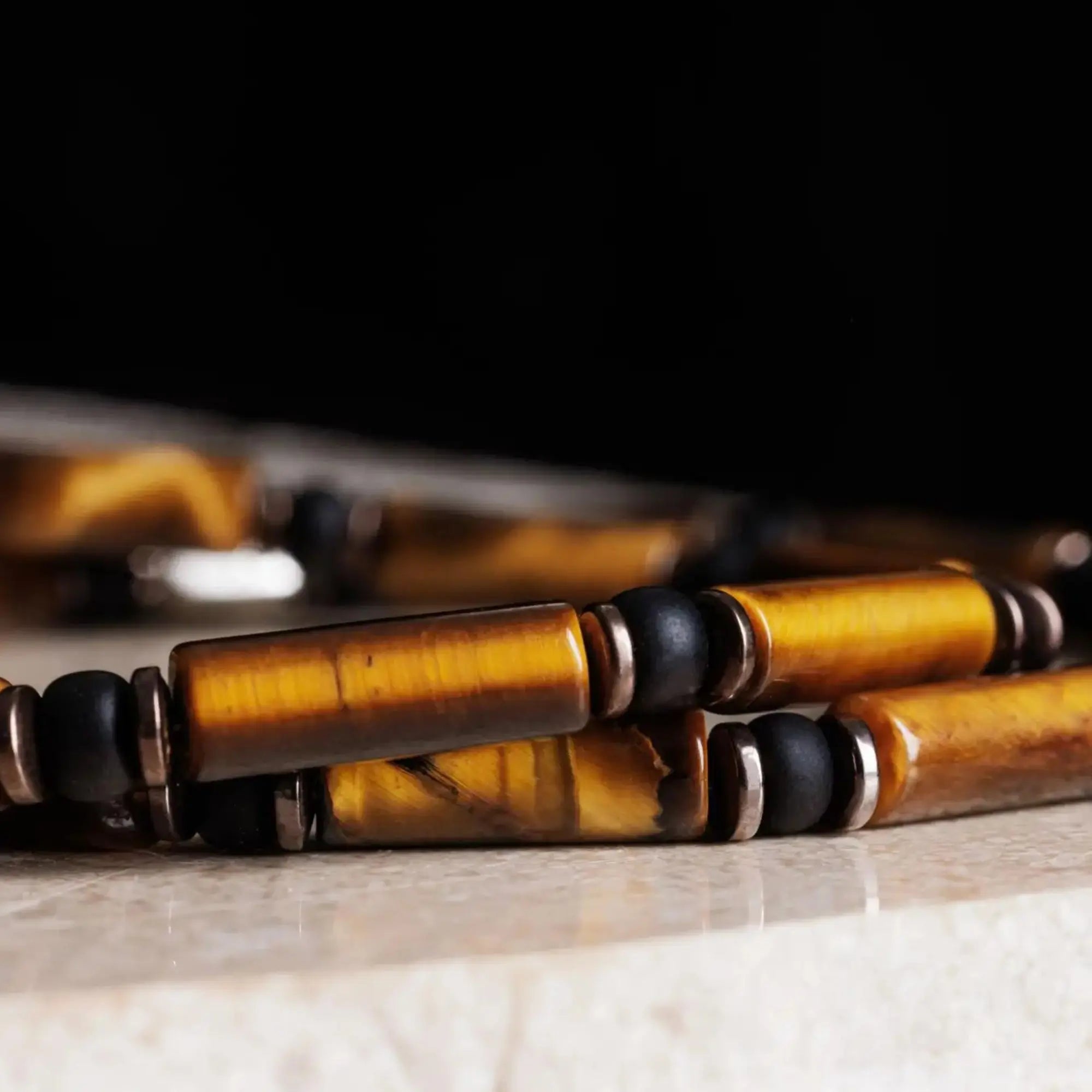 Detail of tiger eye bracelet for men. Close-up of Parvus tube beads showing the golden chatoyant bands. Aurum Brothers.