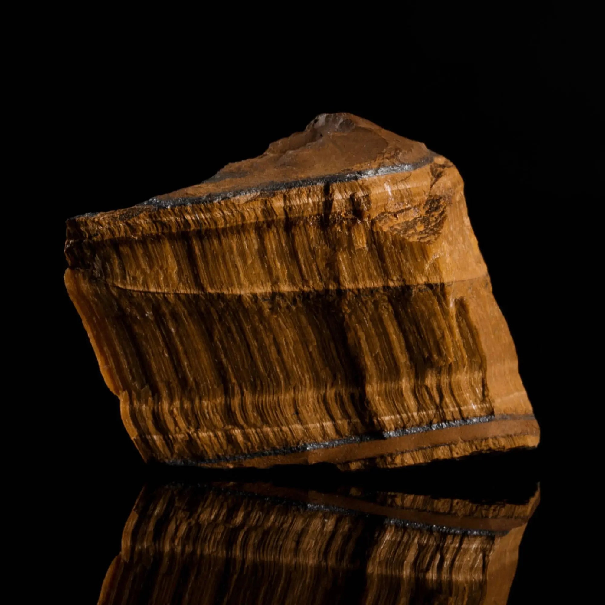 Raw, uncut tiger eye stone showing the natural mineral source. Aurum Brothers.